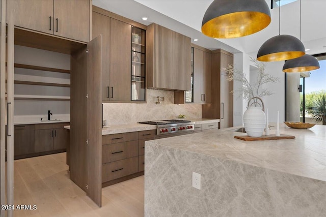 kitchen with a center island, light hardwood / wood-style floors, hanging light fixtures, sink, and tasteful backsplash