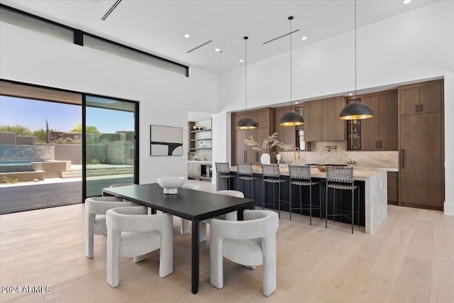 dining space featuring a high ceiling and light hardwood / wood-style flooring