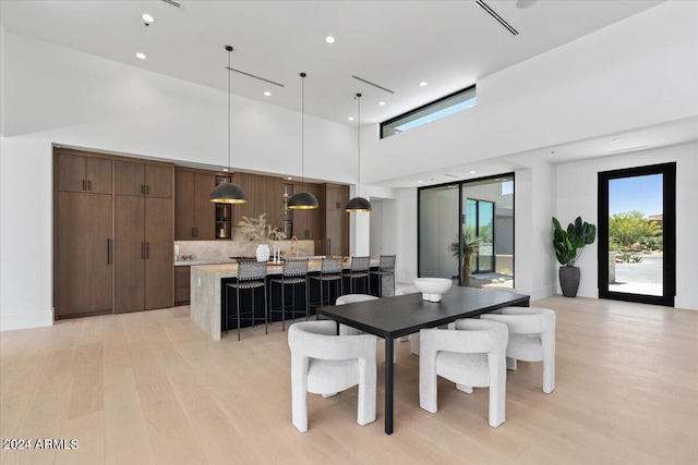 dining area featuring a high ceiling and light hardwood / wood-style floors