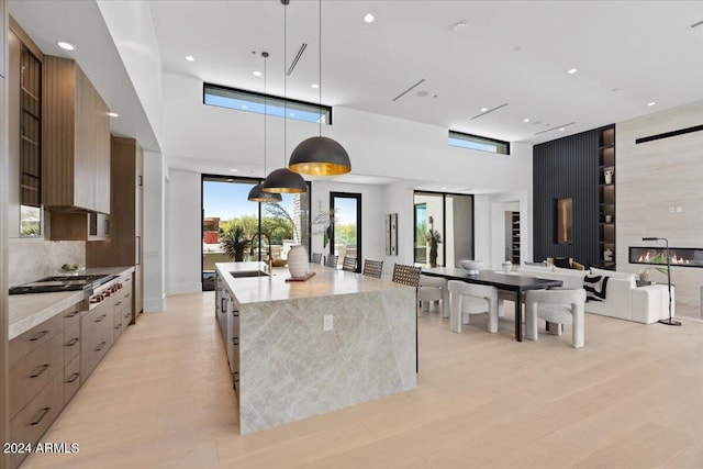 kitchen featuring a large island with sink, decorative light fixtures, sink, and a wealth of natural light