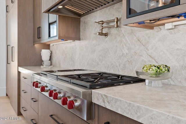 kitchen with tasteful backsplash, stove, and custom range hood