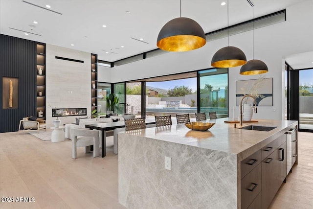 kitchen featuring a healthy amount of sunlight, sink, a fireplace, and a center island with sink