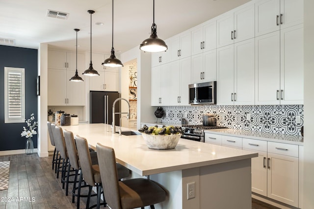 kitchen with pendant lighting, a breakfast bar area, an island with sink, and appliances with stainless steel finishes