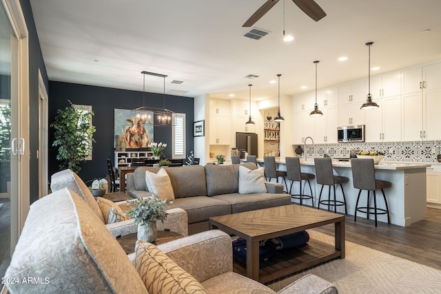 living room with wood-type flooring and ceiling fan with notable chandelier