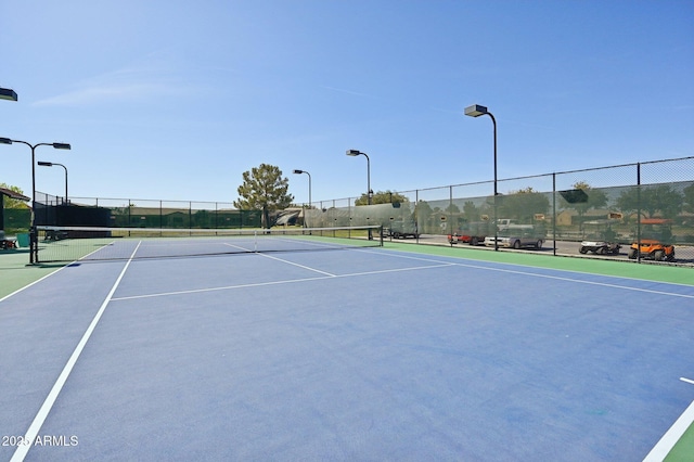 view of tennis court featuring community basketball court and fence