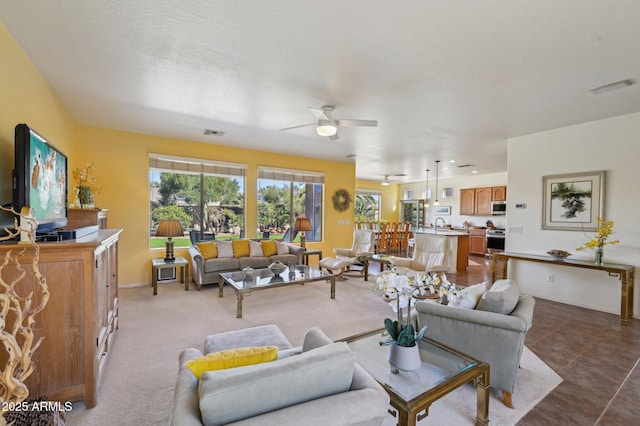 living room with ceiling fan, visible vents, and baseboards