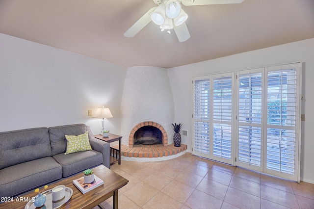 tiled living room featuring a brick fireplace and ceiling fan