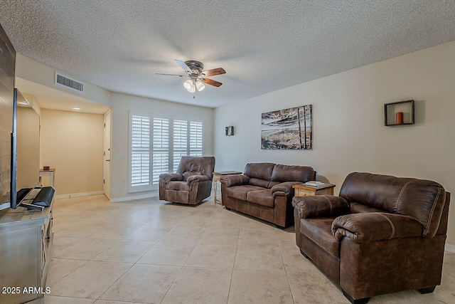 living area with visible vents, light tile patterned flooring, baseboards, ceiling fan, and a textured ceiling