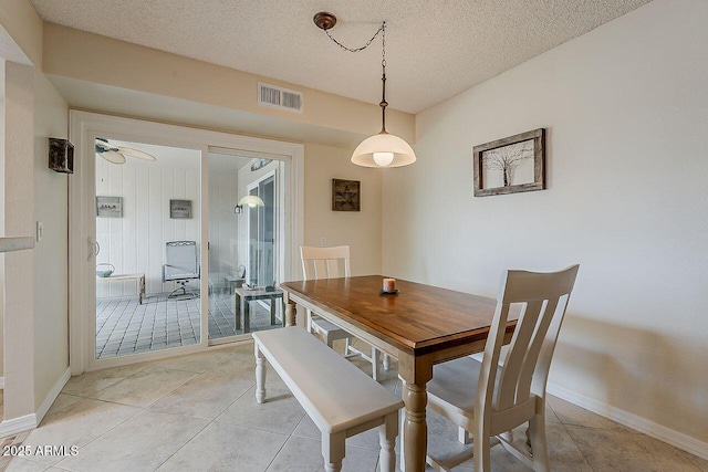 dining area featuring light tile patterned floors, baseboards, a textured ceiling, and visible vents