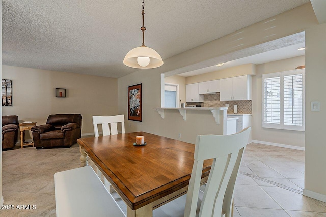 dining area with baseboards, a textured ceiling, and light tile patterned floors