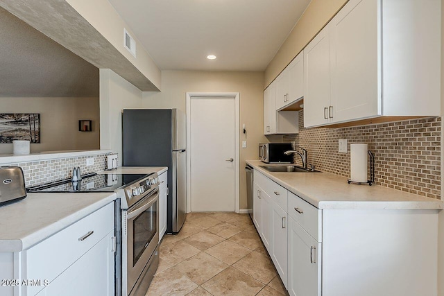 kitchen featuring visible vents, tasteful backsplash, a sink, stainless steel appliances, and white cabinetry