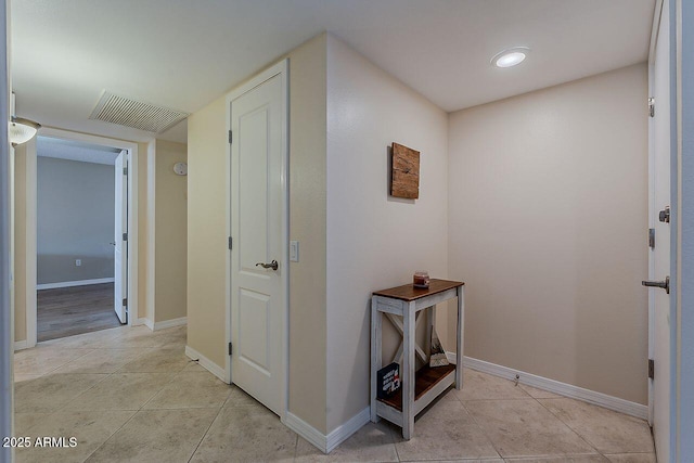 corridor featuring baseboards, visible vents, and light tile patterned floors
