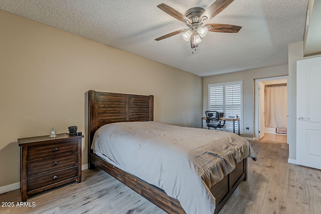 bedroom featuring baseboards, light wood-style flooring, and a textured ceiling