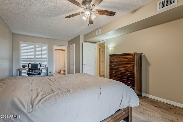 bedroom with baseboards, a textured ceiling, light wood-style flooring, and visible vents