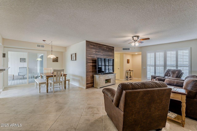 living room featuring a ceiling fan, a textured ceiling, and visible vents