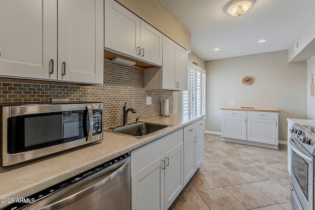 kitchen with white cabinets, a sink, light countertops, stainless steel appliances, and decorative backsplash
