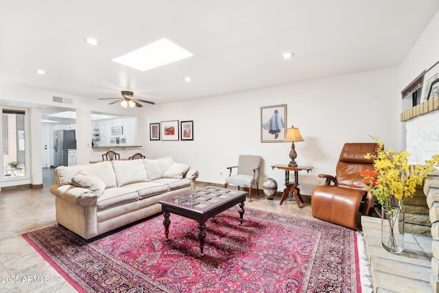 living room featuring ceiling fan and a skylight