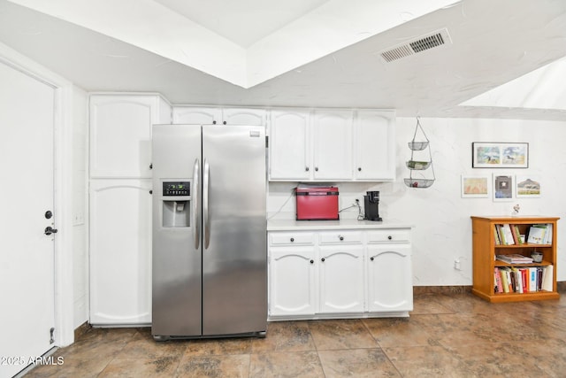 kitchen featuring stainless steel fridge and white cabinets