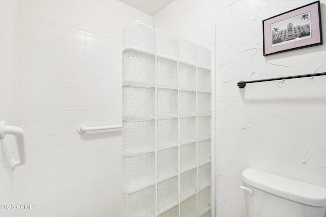 bathroom featuring tiled shower and toilet