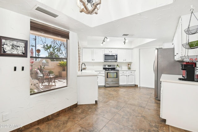 kitchen with stainless steel appliances, white cabinetry, sink, and tile patterned floors