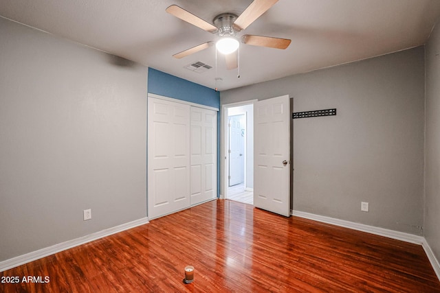 unfurnished bedroom featuring hardwood / wood-style floors, ceiling fan, and a closet