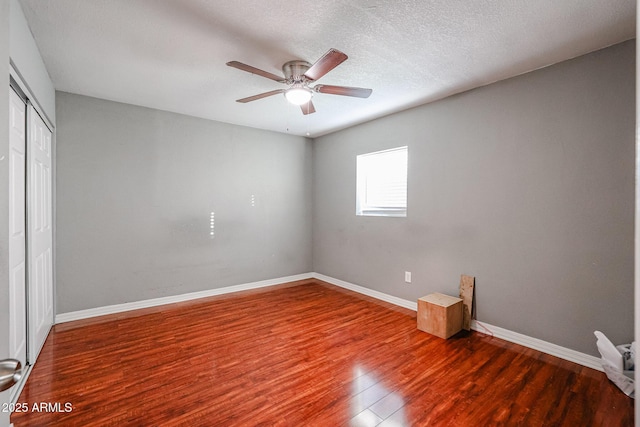 empty room with ceiling fan, wood-type flooring, and a textured ceiling