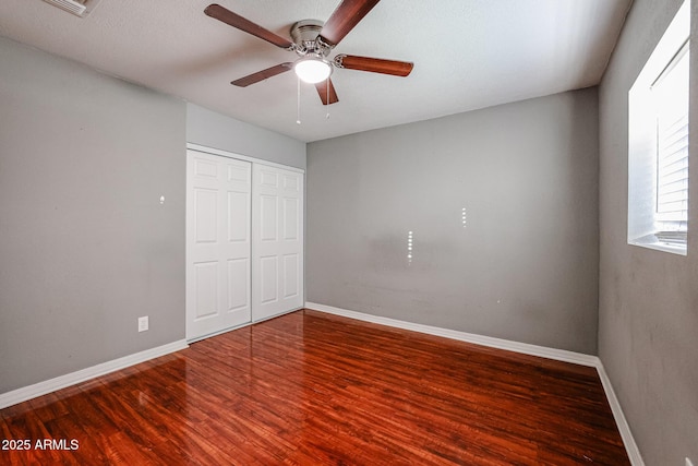 unfurnished bedroom featuring ceiling fan, a closet, and hardwood / wood-style flooring