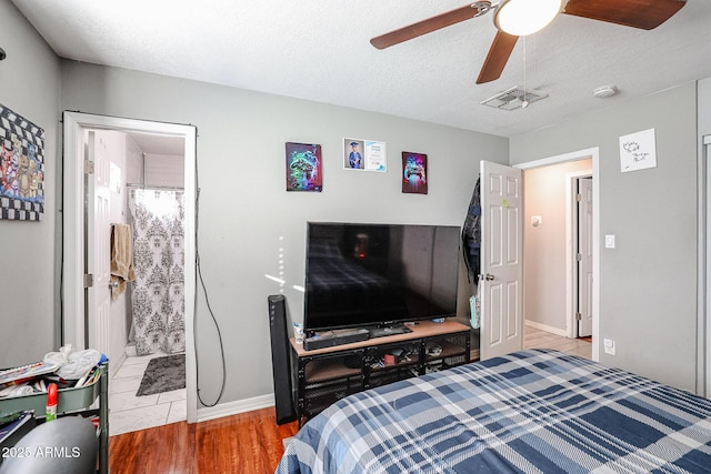 bedroom featuring ensuite bath, ceiling fan, a textured ceiling, and hardwood / wood-style flooring