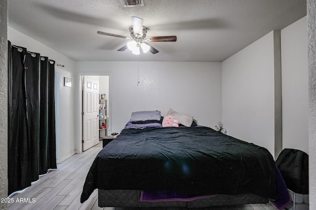 bedroom featuring ceiling fan, a textured ceiling, and light wood-type flooring