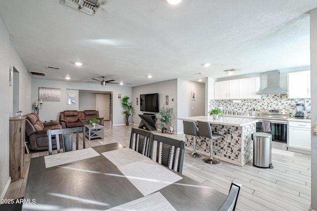 dining room with ceiling fan, light hardwood / wood-style floors, and a textured ceiling