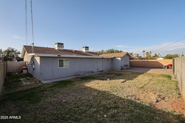 rear view of property featuring a yard, central AC, and a patio area