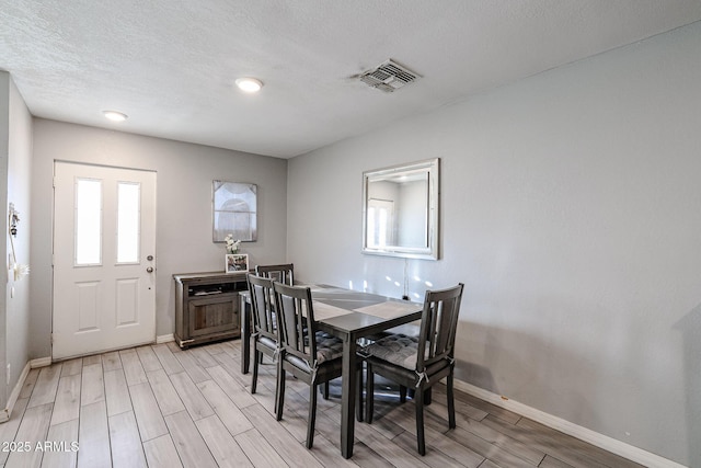 dining room featuring a textured ceiling and light hardwood / wood-style flooring