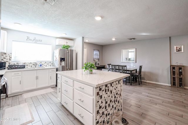 kitchen featuring a kitchen island, white cabinetry, stainless steel appliances, and a wealth of natural light