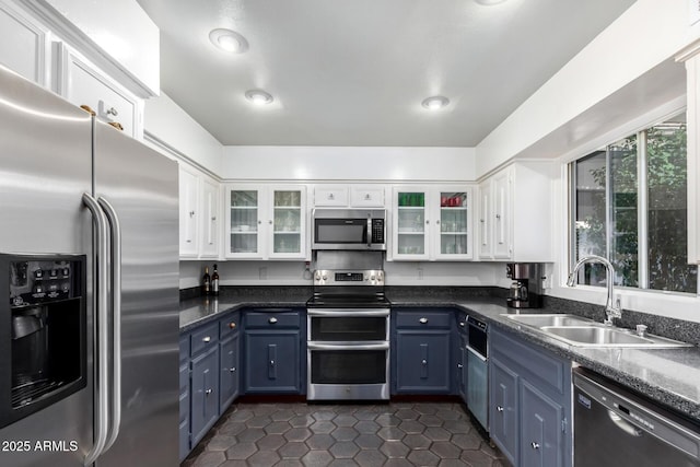 kitchen featuring white cabinets, dark tile patterned flooring, blue cabinets, sink, and appliances with stainless steel finishes