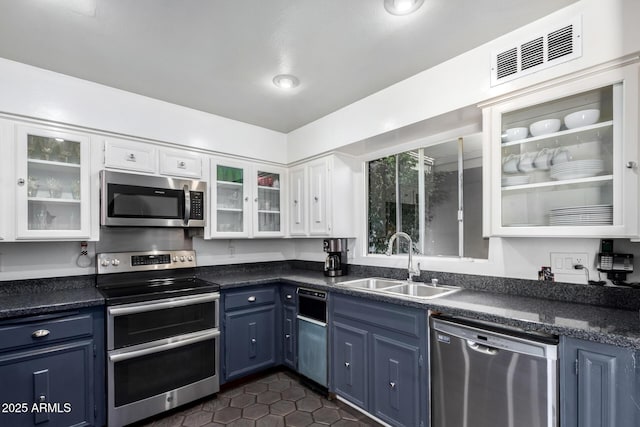 kitchen with stainless steel appliances, dark tile patterned floors, sink, blue cabinetry, and white cabinets