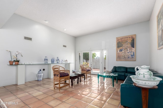 living room featuring a towering ceiling, french doors, light tile patterned floors, and a textured ceiling