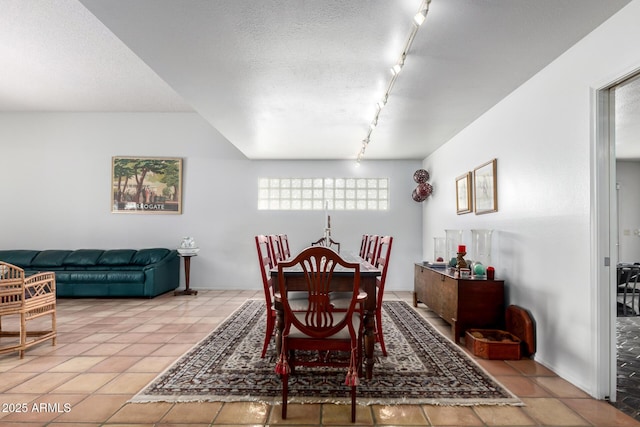 tiled dining space with a textured ceiling and rail lighting