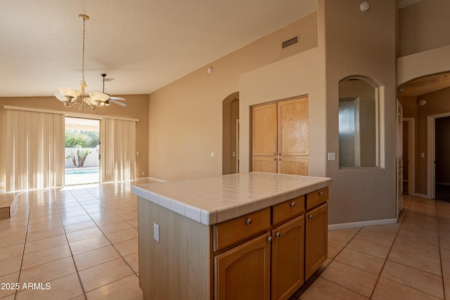 kitchen featuring light tile patterned floors, decorative light fixtures, tile countertops, a kitchen island, and lofted ceiling