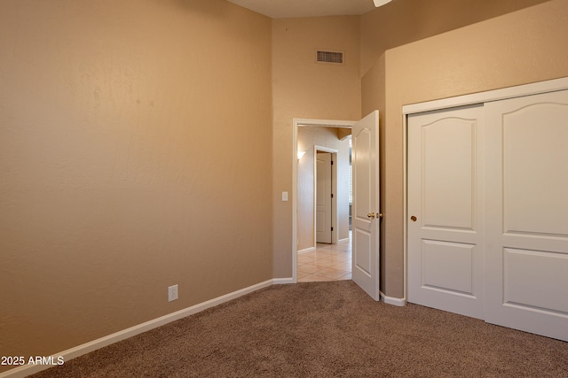 unfurnished bedroom featuring light colored carpet and a closet