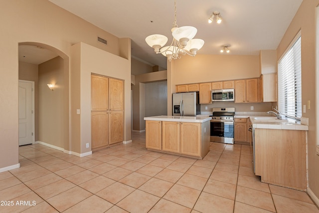 kitchen with light tile patterned floors, a notable chandelier, decorative light fixtures, a kitchen island, and appliances with stainless steel finishes