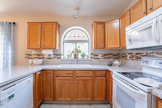 kitchen featuring light tile patterned floors, decorative backsplash, white appliances, light stone countertops, and sink