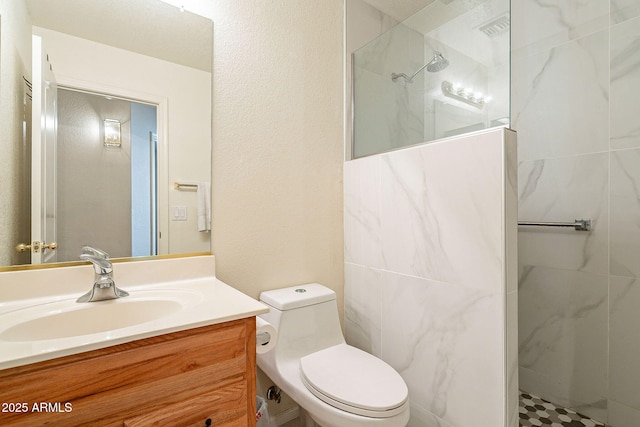 bathroom with toilet, tiled shower, and vanity