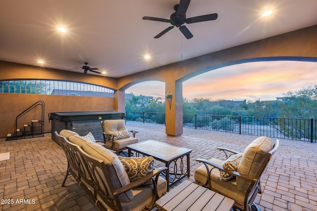 patio terrace at dusk featuring an outdoor living space, a hot tub, and ceiling fan