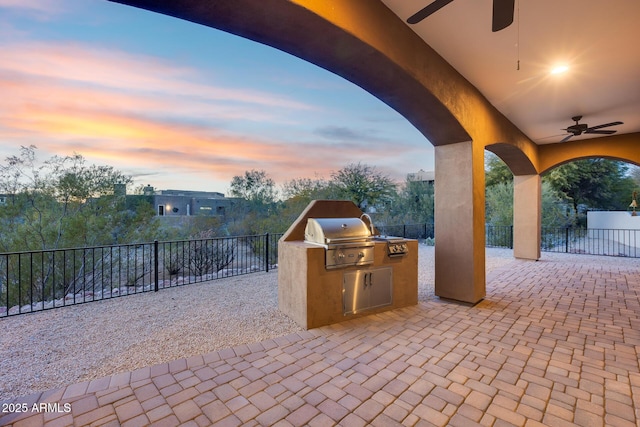 patio terrace at dusk featuring area for grilling and ceiling fan