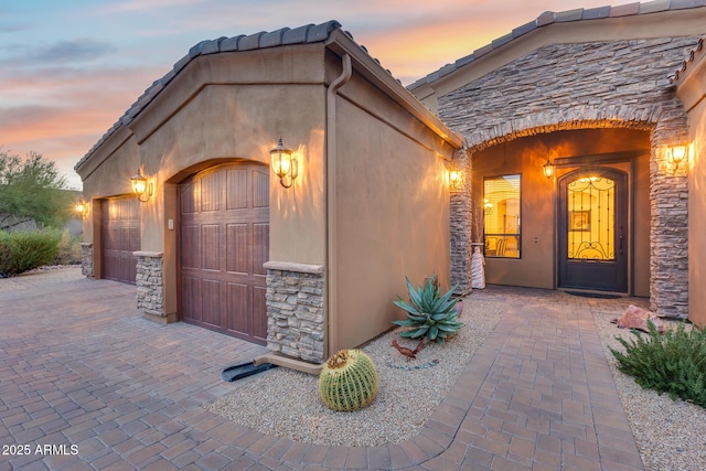 exterior entry at dusk featuring a garage