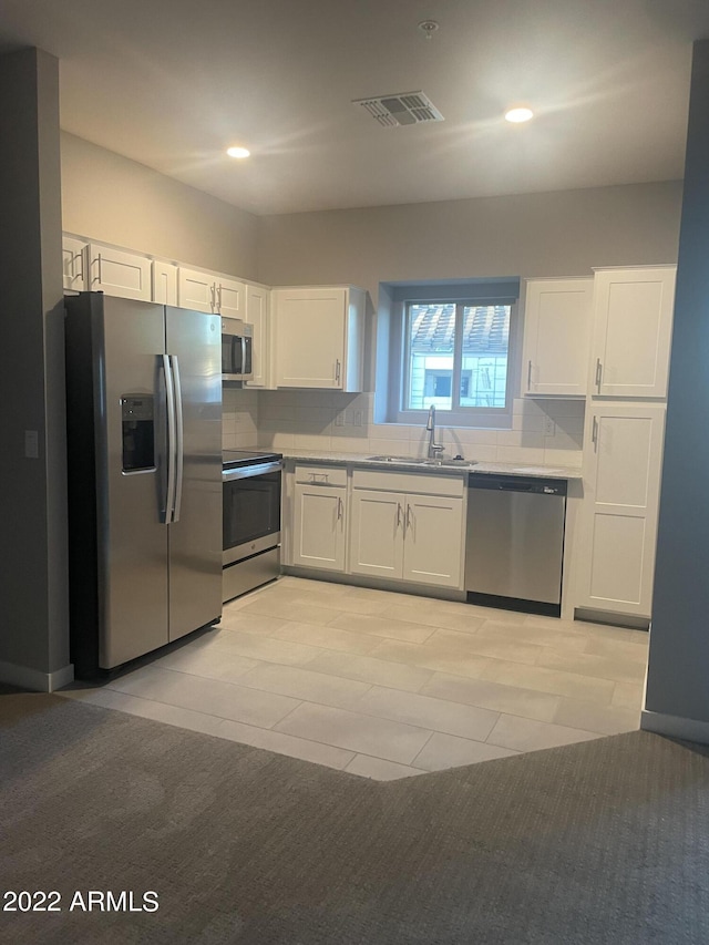 kitchen featuring a sink, appliances with stainless steel finishes, visible vents, white cabinets, and decorative backsplash
