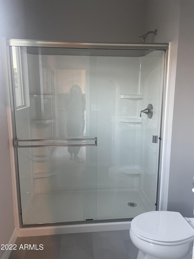 bathroom featuring a stall shower, tile patterned floors, and toilet