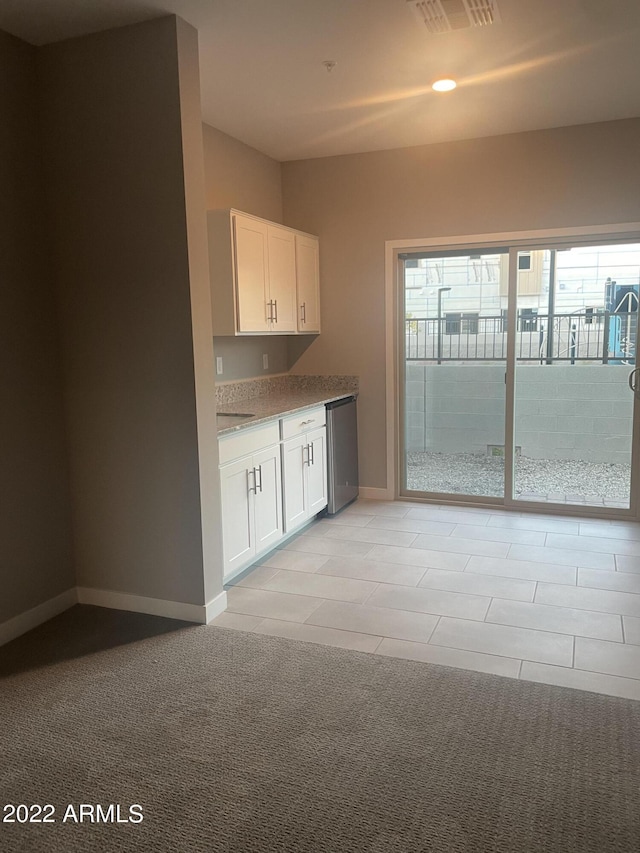 kitchen with baseboards, white cabinetry, visible vents, and light carpet