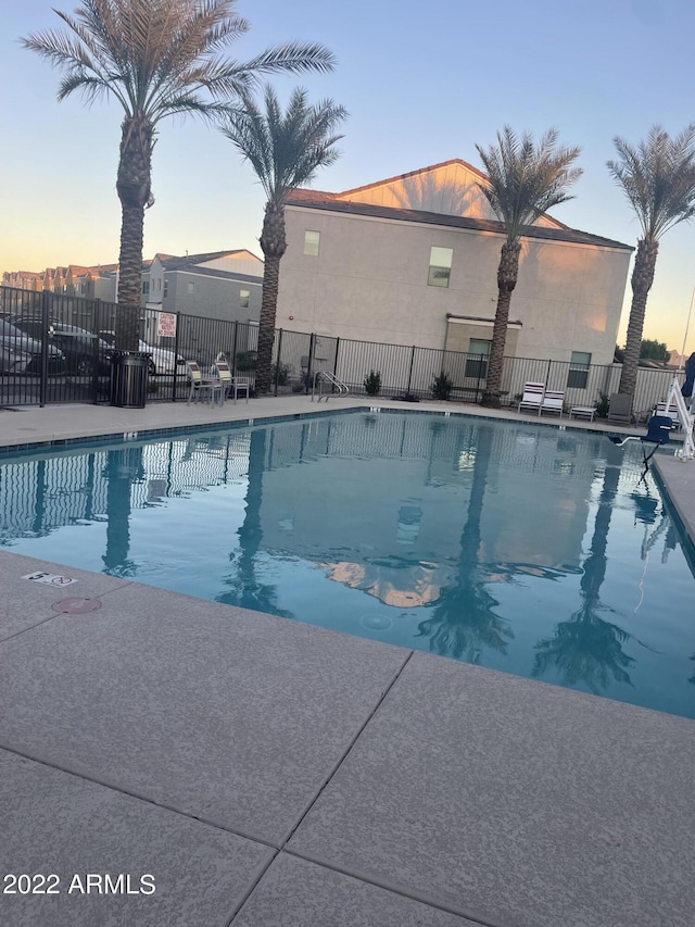 community pool with a patio area and fence