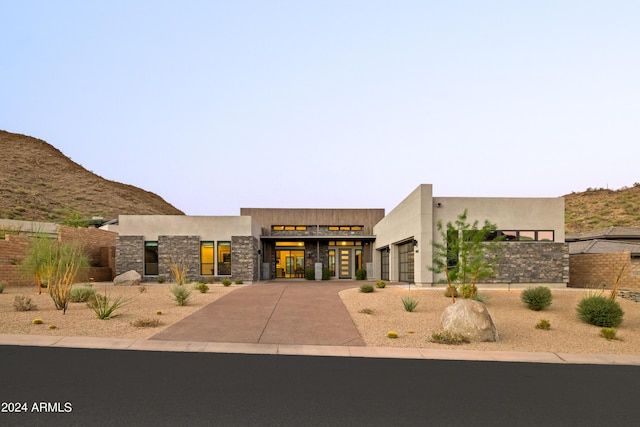 view of front of house featuring driveway, stone siding, and stucco siding